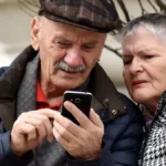 Двоє пенсіонерів дивляться в телефон