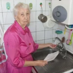 Пенсіонерка біля крану з водою