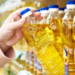 Рука бере пляшку олії