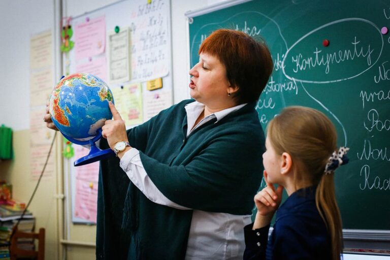 Вчителька показує учениці глобус