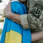 Військовий обнімає жінку в прапорі