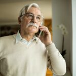 Пенсіонер розмовляє по телефону