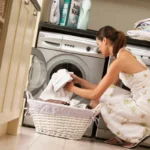 Жінка кладе речі в пральну машину