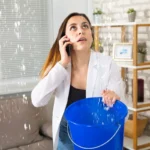 Жінка тримає відро, вода капає зі стелі