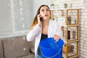 Жінка тримає відро, вода капає зі стелі