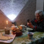 Женщина сидит в темноте с телефоном